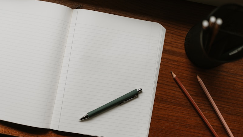 An open notebook with pen and pencils on a desk