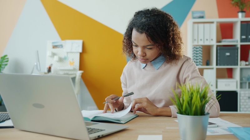 A founder working alone at a desk with a laptop and notebook
